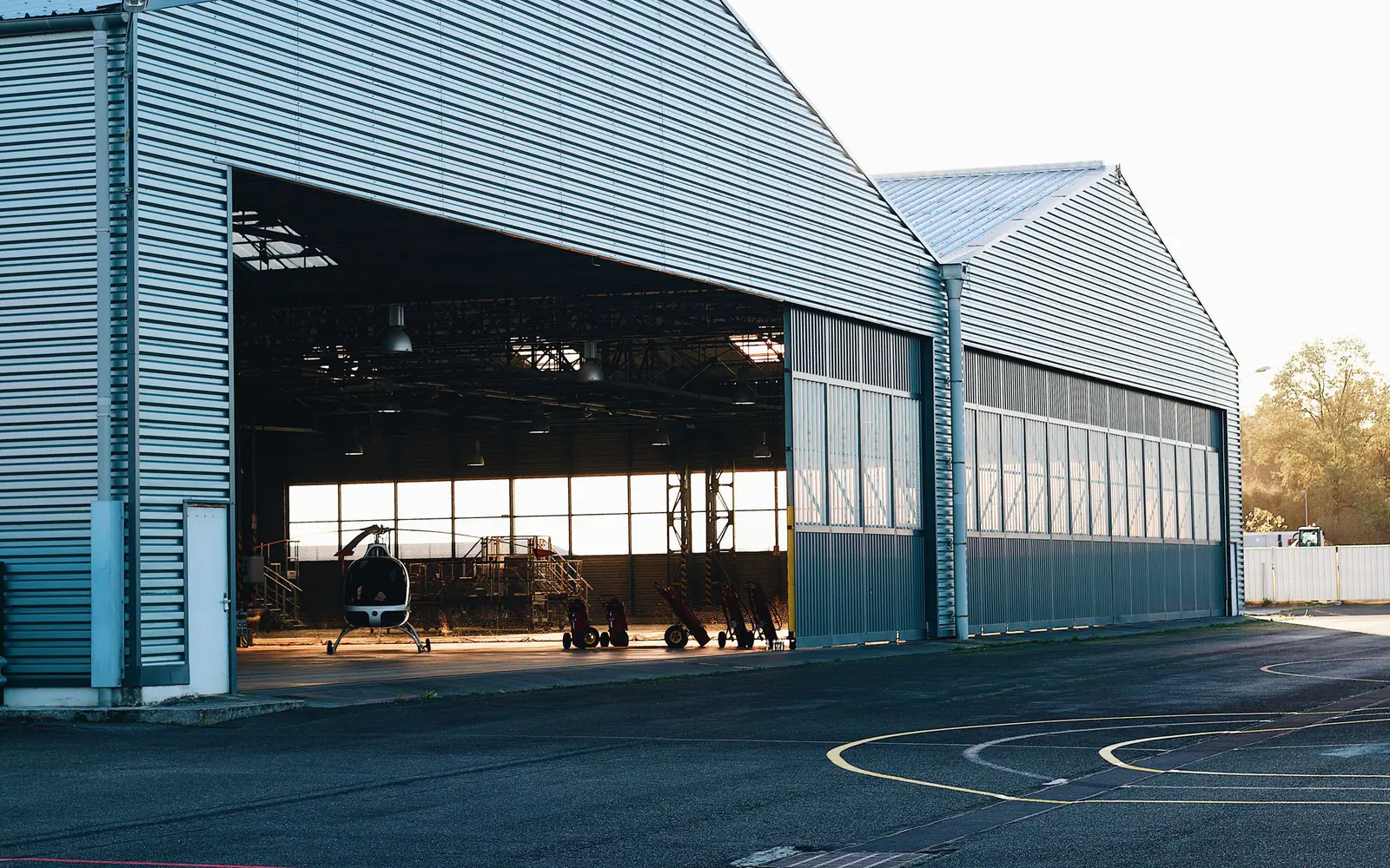 A modern aircraft hangar with its doors open onto the apron