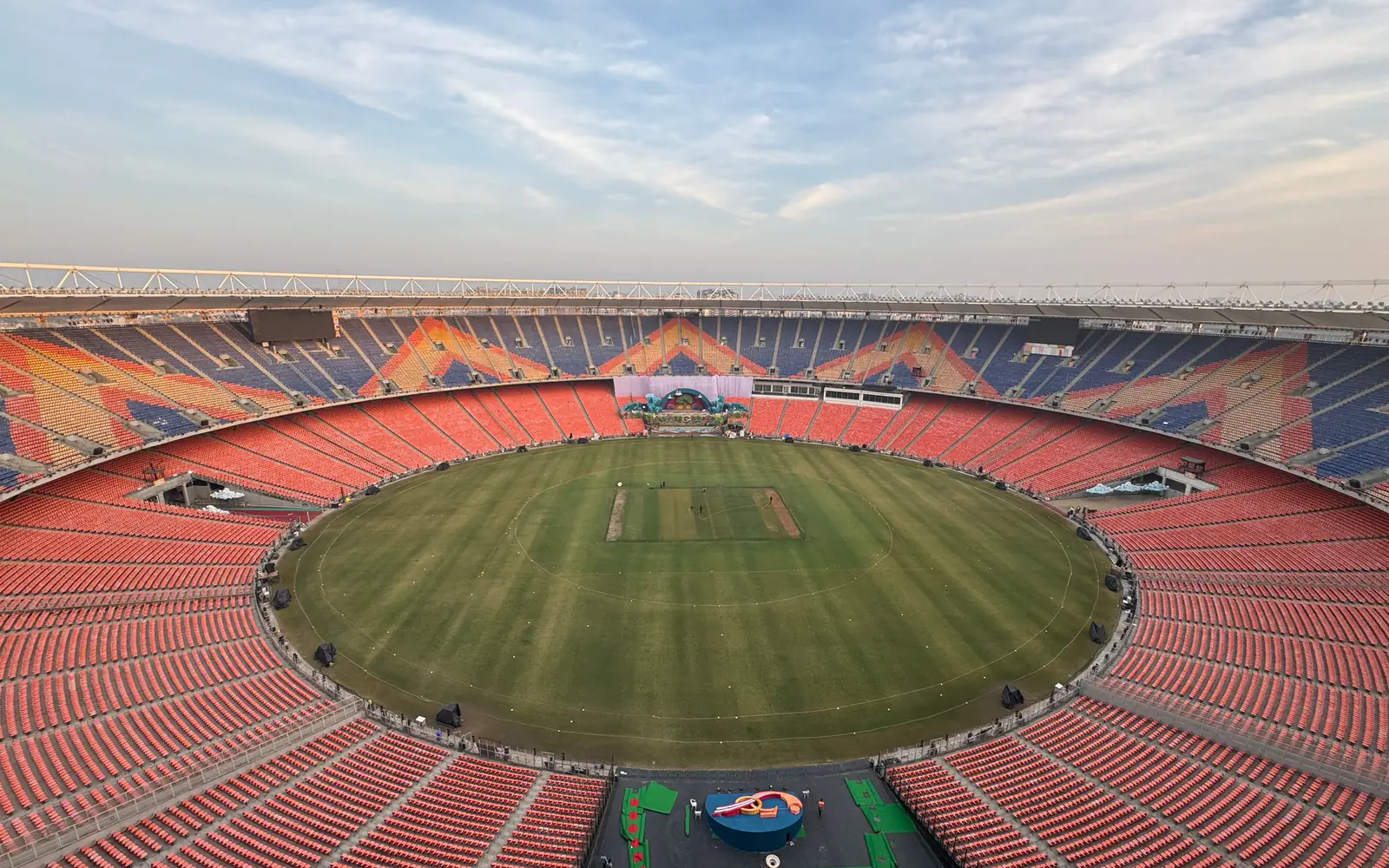A cricket stadium bowl seen from the upper tier at dusk