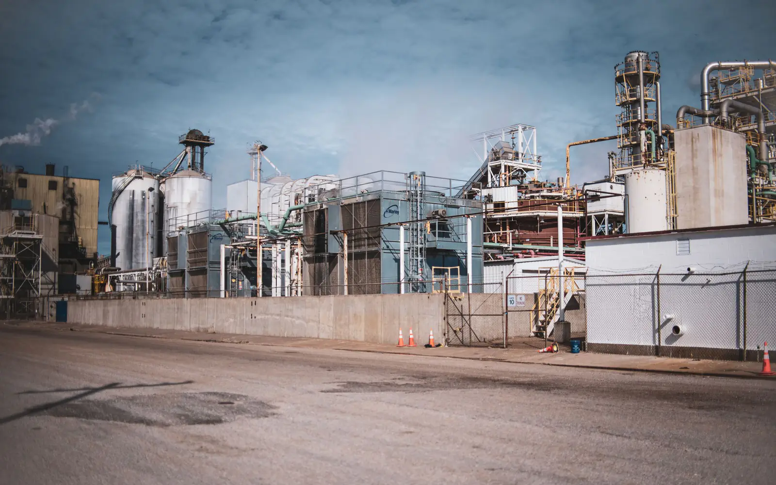 A large industrial process plant seen across an access road