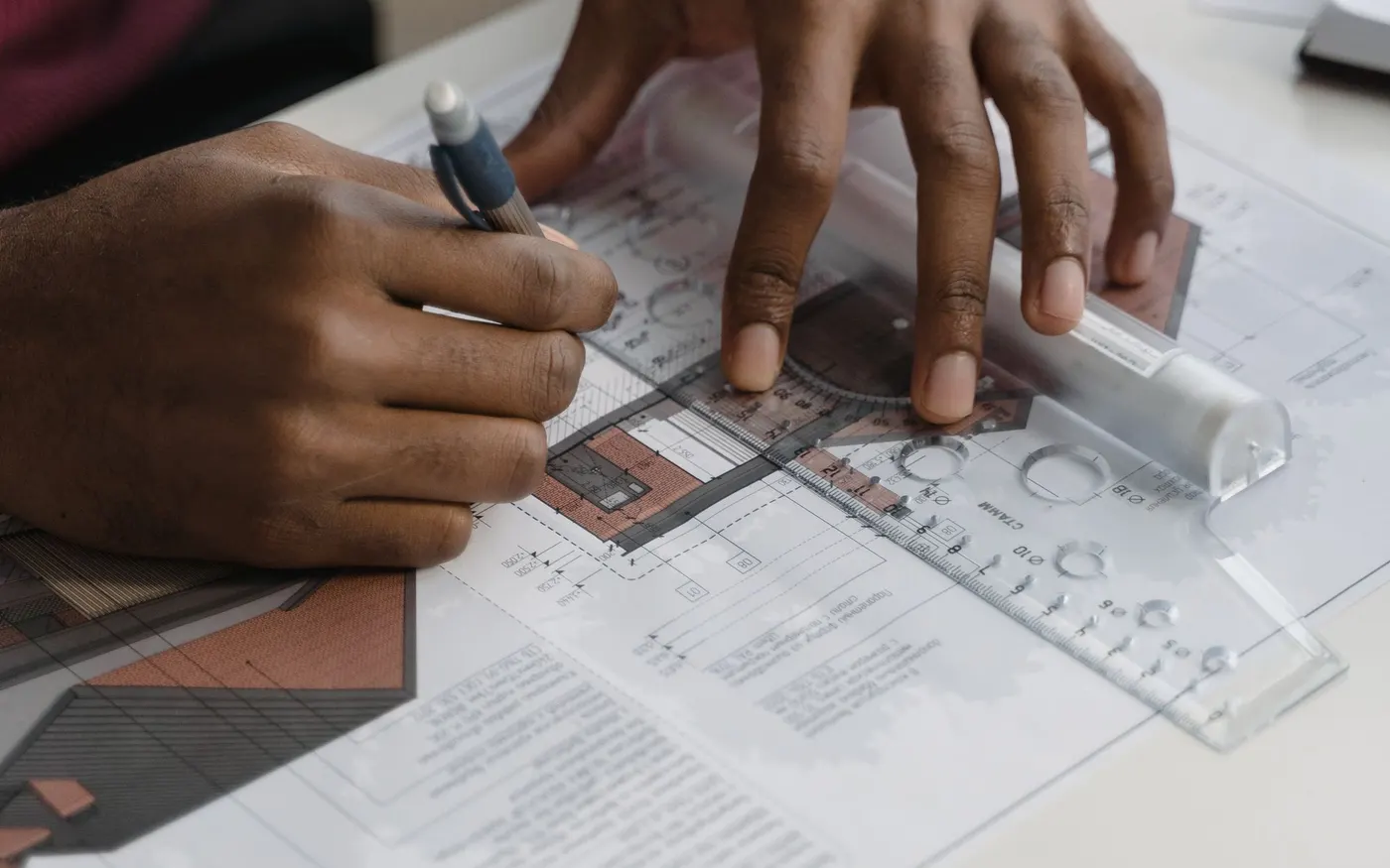 Hands drawing a plan with a ruler and pencil