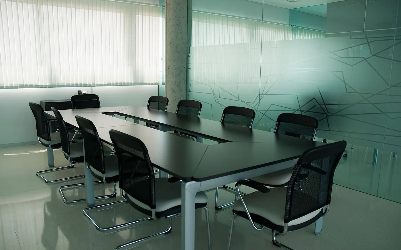 An empty boardroom with a long table and glass walls
