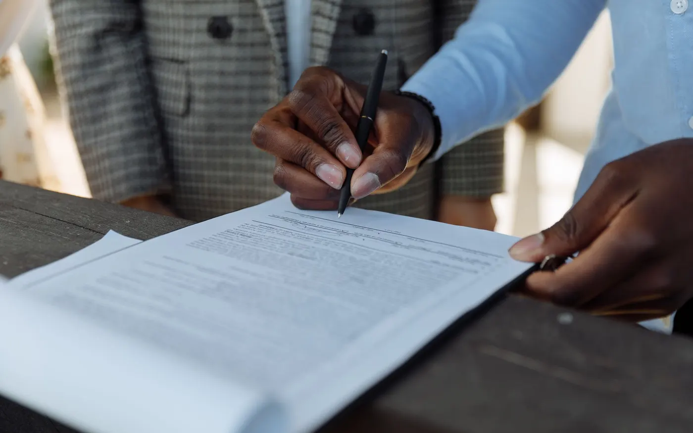 People signing a document across a table