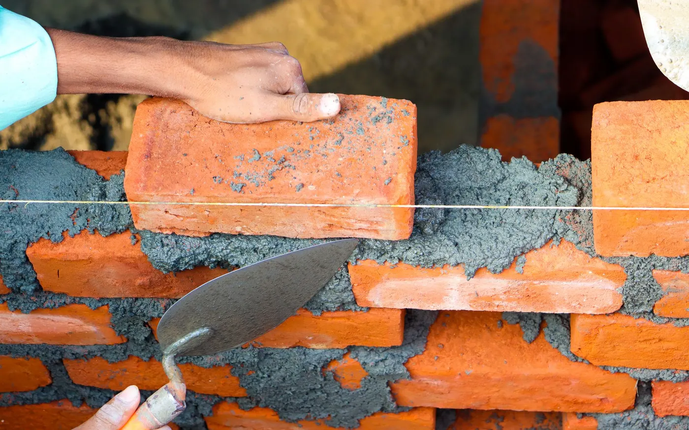 Hands laying bricks in mortar