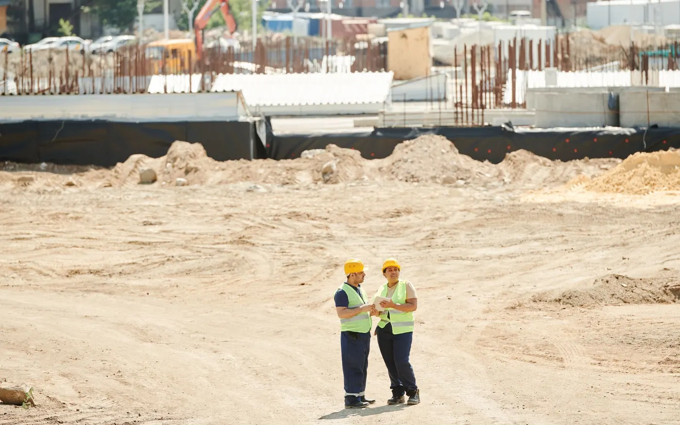 Two workers discussing drawings on a construction site